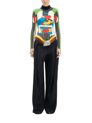 Person wearing a colorful, abstract-patterned long-sleeved top with black pants by Jean Paul Gautier