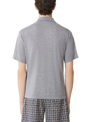 Person wearing a gray polo shirt and patterned shorts 