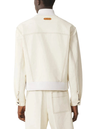 Person wearing a cream-colored jacket with a brand logo on the back by Lanvin
