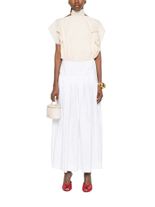 Woman wearing a cream blouse and white skirt by Lanvin with red shoes 