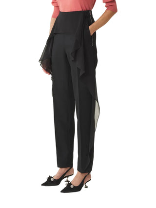 Person wearing black pants with ruffled details 