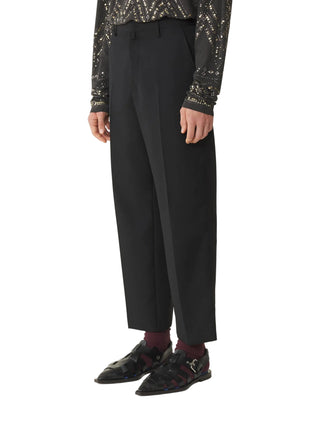 Person wearing black trousers with a patterned top by Lavin