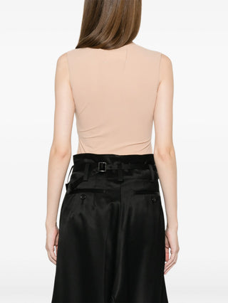 Person wearing a beige sleeveless top and black high-waisted pants 