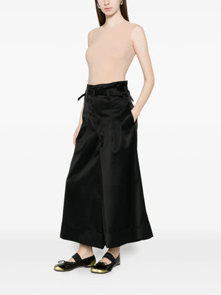 Person wearing a beige bodysuit with black pants and black shoes by Maison Margiela