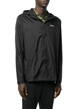 Person wearing a black rain jacket with a brand logo by Patagonia