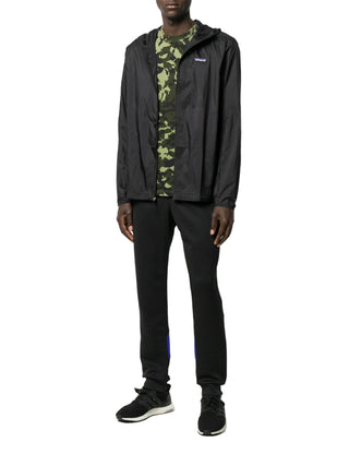 Person wearing a black jacket by Patagonia with a camouflage shirt, black pants and sneakers