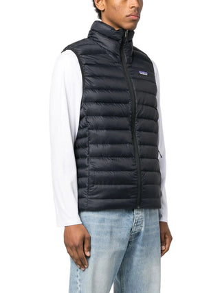 Person wearing a black puffer vest over a white shirt with a light blue jeans 