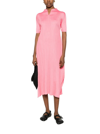 Person wearing a pink dress with black shoes by Pleats Please Issey Miyake