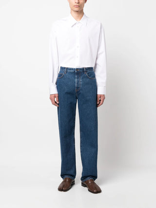 Person wearing a white shirt and blue jeans by The Row