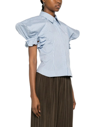 Person wearing a blue and white striped shirt with puffed sleeves and brown trousers