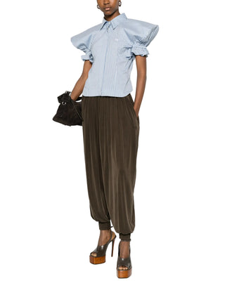 Person wearing a blue ruffled blouse with brown pants and brown heels