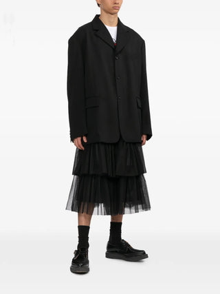 Black Comme Des Garçons black wool blazer with button fastening and flap pockets — available at our Lisbon store.