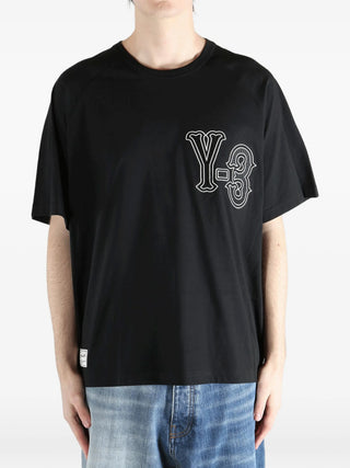 Person wearing a black t-shirt with a logo by Y-3