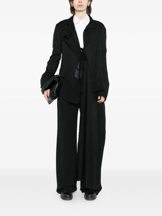 Person wearing a black suit with a white shirt by Yohji Yamamoto